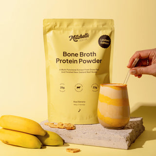 Mitchell's Bone Broth Protein Powder with a glass of protein shake and bananas on a yellow background